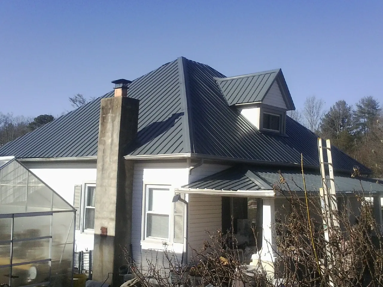 Dark blue standing seam metal roof on a white farmhouse with dormer — Slate & Tile Roof Repair by Roofing Brothers in Wonalancet