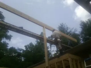 Carpenter setting a ridge beam over a new addition frame — Ice Dam Removal by Roofing Brothers in Wonalancet