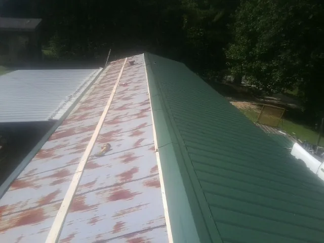 Old rusted panels beside newly installed green metal roofing — Wind Damage Roof Repair by Roofing Brothers in Wonalancet