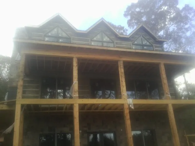 Dormers and porch framing on a large log home under construction — Roof Coating work by our crew in Wonalancet