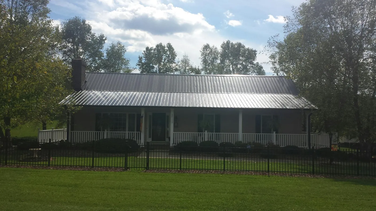 Gray metal roof on a brick ranch with a full width front porch — Gutter Guard Installation work by our crew in Wonalancet