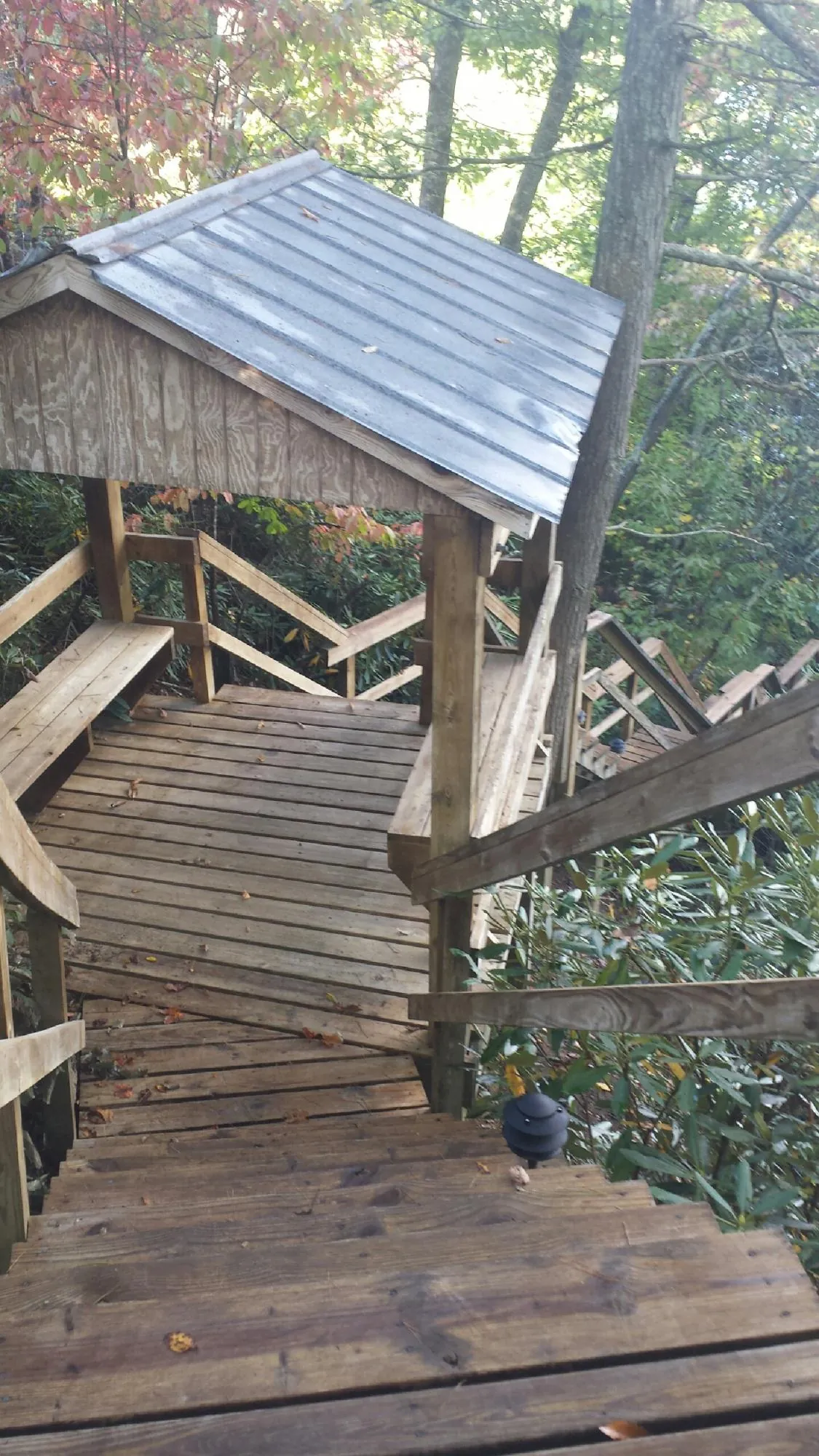 Metal roofed shelter over wooden steps on a wooded walkway — Skylight Repair & Installation work by our crew in Wonalancet