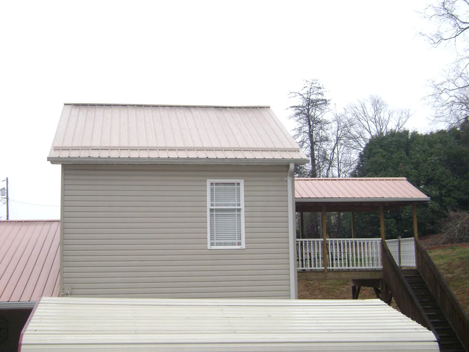 Tan metal roofs on a two story addition and attached porch, from a Roof Replacement job in Wonalancet