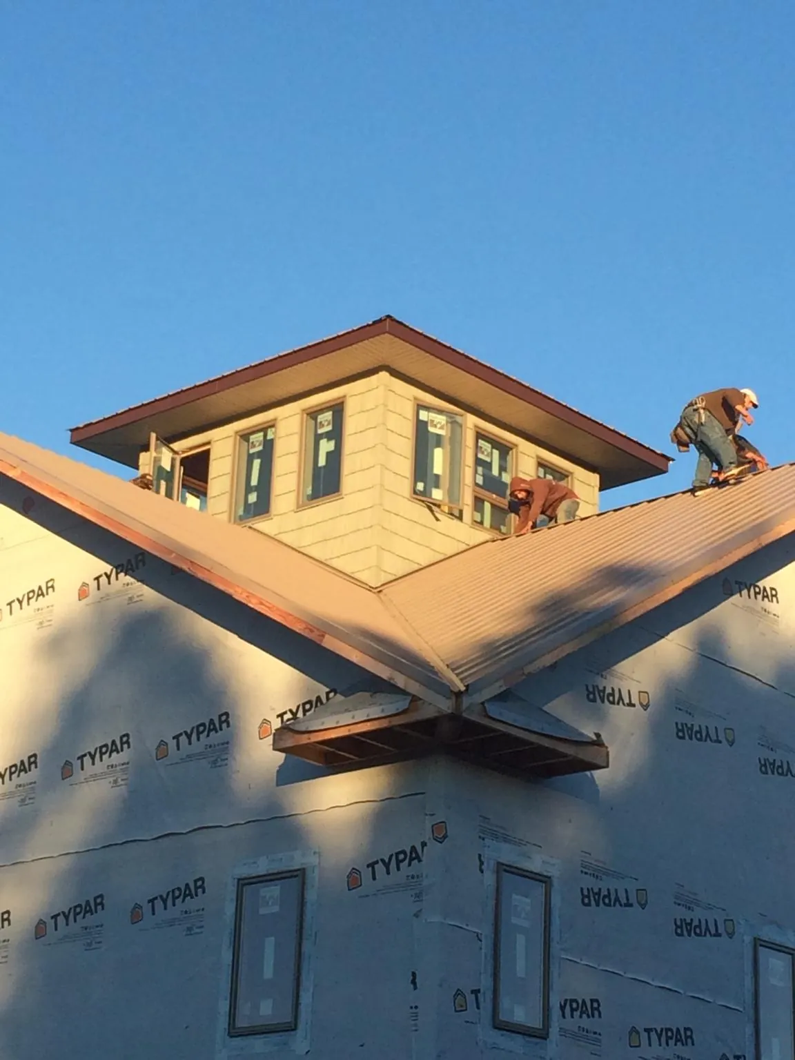 Roofers working around a rooftop cupola on a new metal roof at sunset — Roof Waterproofing in Wonalancet by Roofing Brothers